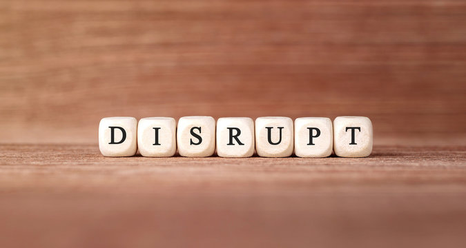 Word DISRUPT made with wood building blocks