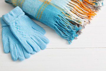 blue gloves and scarf on wooden white background