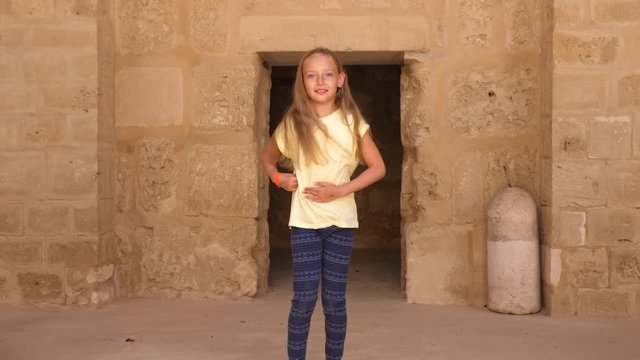 Young pretty girl dancing at beige stone background