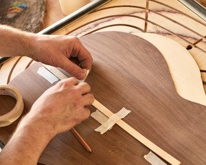 Marking and gluing of footer to the back deck of classical guitar. Production of classical guitar.