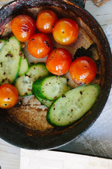 Fresh and ripe vegetables - tomatoes and cucumbers, roasted on fry pan.