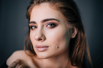 Fototapeta premium beauty portrait. Studio portrait of a beautiful girl on a gray background. Good make-up. Face close-up