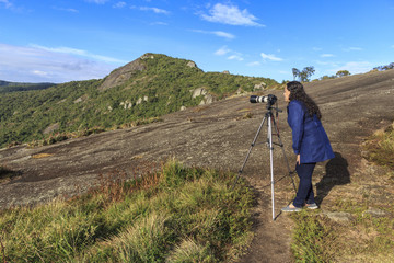 woman photographer taking photo on mountain peak