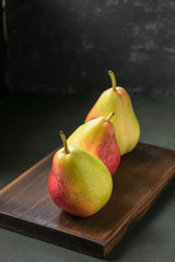 Three ripe pears on a dark wooden board