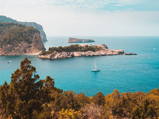 Vista aerea desde uno de los acantilados de la zona del puerto de San Miguel. Barcos de recreo, aguas turquesas y pqueñas islas, al atardecer. Un destino relajante y paradisiaco.