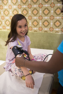 Little multicultural girl on a doctor well-visit, getting blood pressure measured