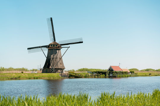 Windmill and water canal at sunny day in Kinderdijk, southern Holland.