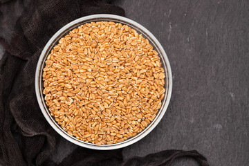 spelt in glass bowl on black ceramic background
