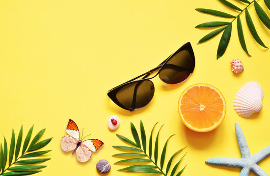 Tropical Background. Palm Trees Branches with starfish and seashell on yellow background. Travel. Copy space.