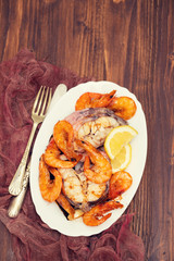 boiled fish with shrimps and lemon on white dish