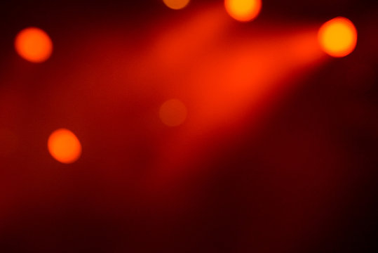 Abstract magic image with rays of colored light from floodlights in the dark and red bokeh photo
