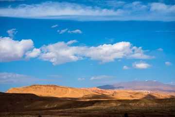 African landscape with sand dunes and Atlas mountain in Sahara desert with bright blue sky and clouds in Morocco