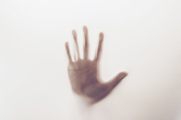 Silhouette of hand behind glass foreground
