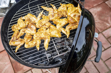Chicken wings are cooked on the grill, close-up. Outdoors.