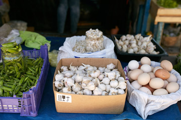 Display of fresh green and white onions, garlic, eggs, peas and pumpkin seeds. Fruits and vegetables at a farmers summer market.