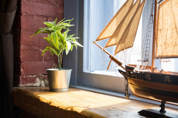 Model of a boat and flower in a pot on a wooden window sill in an old house