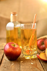 Homemade apple juice with ice, red apples, straw, still life on a wooden table vertical photo