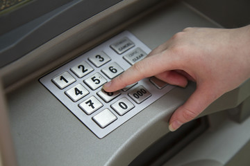 Close-up of hand entering PIN pass code on ATM bank machine keypad