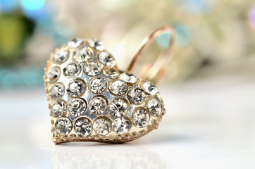 Heart shaped earring decorated with diamonds - elegant reflection - colored background blue - warm color balance