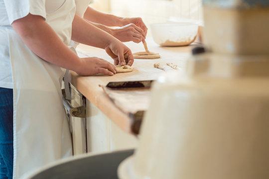 Frauen in der B&auml;ckerei Backstube formen Teil zu Brezeln, die dann gebacken werden