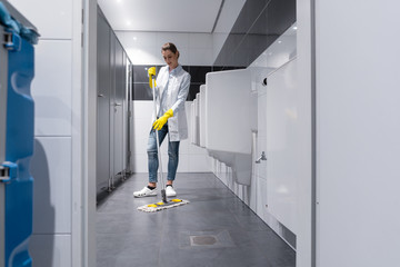 Klofrau oder Putzfrau reinigt Urinal in Herrentoilette 