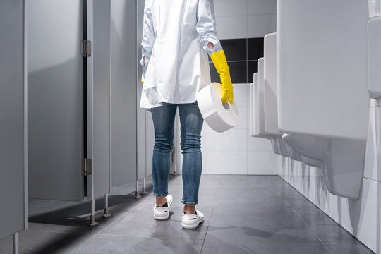 Klofrau oder Raumpflegerin wechselt Klopapier in Toilette 