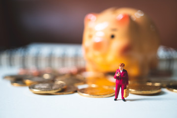 Miniature people, woman standing on piggy bank and stack coins background using as business, finance and job retirement concept