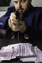 A man in suit with a gun directed. Cash, hundreds of euros aducted with the help of a pistol, a crime, robbery