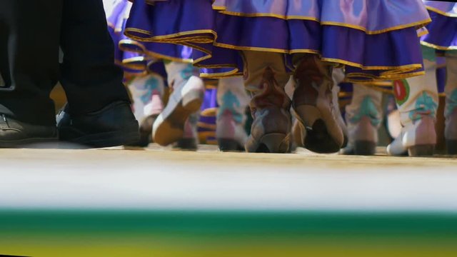 Legs of ladies in folk national tatar leather boots and long skirts walks on stage