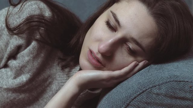 Depressed sad lonely attractive woman lying on sofa, thinking his ex husband