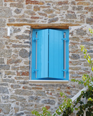vibrant blue shutters window on stone wall