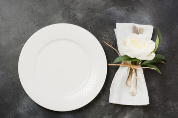 Romantic dinner. Table setting with white peony on black table. Top view.