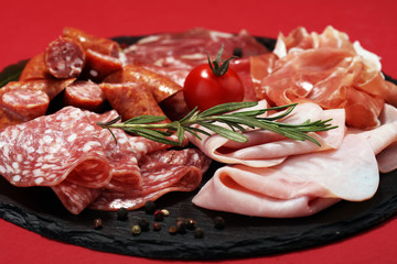 Food tray with delicious salami, ham,  fresh sausages and herbs. Meat platter with selection