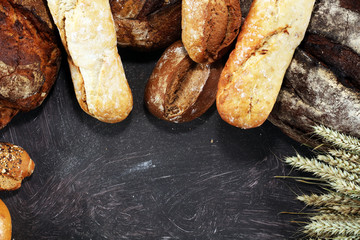 Different kinds of bread and bread rolls on board from above. Kitchen or bakery