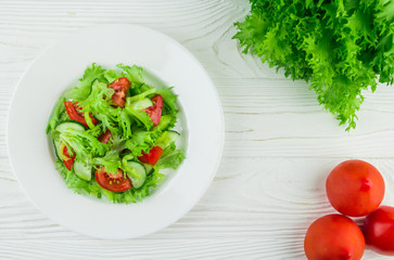 salad of tomatoes, cucumbers and lettuce leaves, on a wooden background