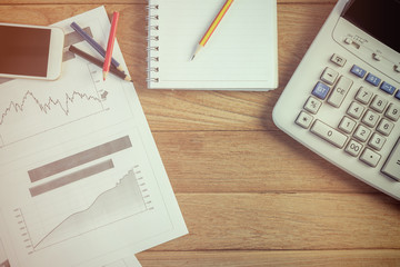 Investment charts with laptop and calculator on wooden table workplace