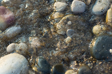 pebble stones on the sea beach, the rolling waves of the sea with foam