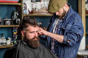 Hipster lifestyle concept. Hipster client getting haircut. Barber with hair clipper work on...