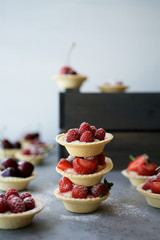 Small tartas with berries. Fresh dessert on gray background
