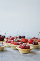 Small tartas with berries. Fresh dessert on gray background
