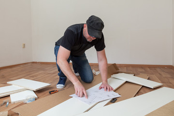 Man dressed casual assembling furniture in new house. Carpenter repair and assembling furniture at home