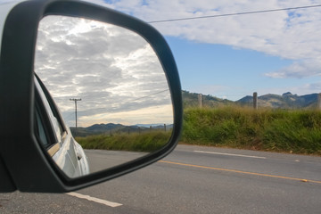 Road and cloud seen from the car mirror