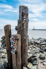 Bundles of locks on a beach by the lake with a lighthouse in the background