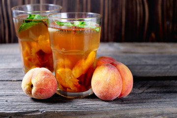 Peach ice tea in a glass with mint on wooden table
