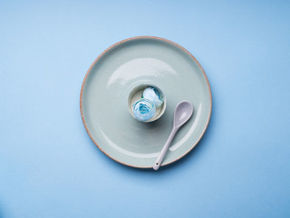 Blue pastel ceramic dish with flowers and spoon. Abstract food, tableware crockery, table setting monochrome concept