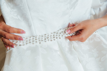 Bride putting on the wedding dress with a decorated belt