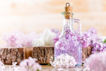 Obraz na płótnie Canvas Tincture of lilac in a refined glass vial and lilac flowers of different shades on a wooden cut.