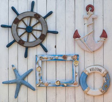 marine concept, steering wheel, life ring and anchor on a white wooden wall