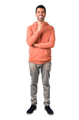 Fototapeta premium Full body of Man in a pink sweatshirt taking a magnifying glass and showing teeth through it on isolated white background