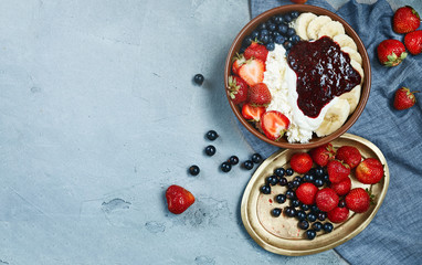 bowl of cottage cheese with berries, bananas and sour cream. fresh berries on wintage copper plate